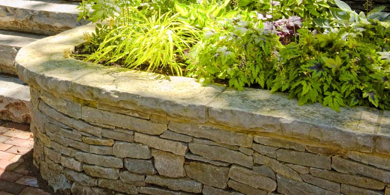 An image of a retaining wall made out of flagstone with a garden at the top.